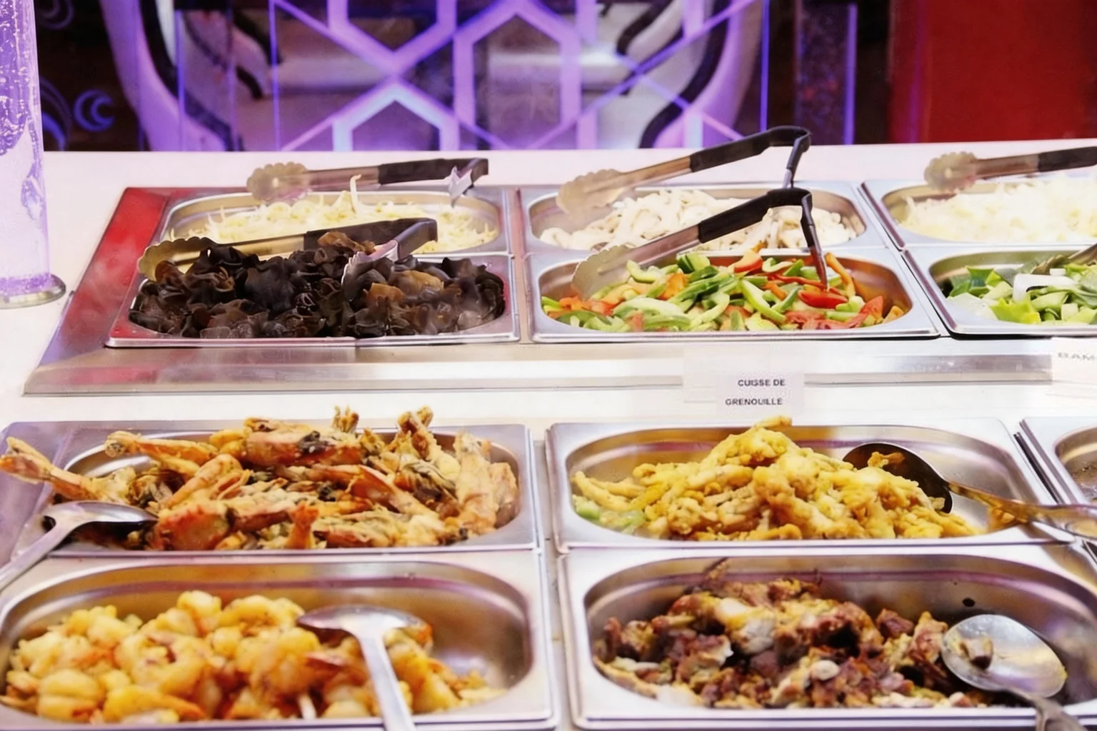 Bacs du buffet en inox : champignons noirs, légumes, beignets, étiquette « Cuisse de grenouille »
