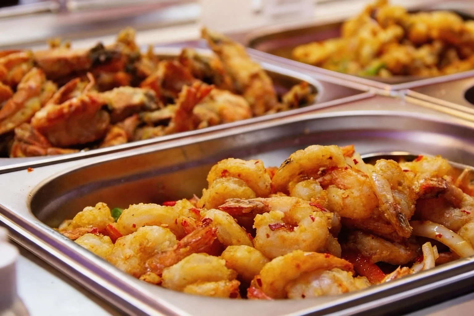Crevettes et beignets dans des bacs en inox